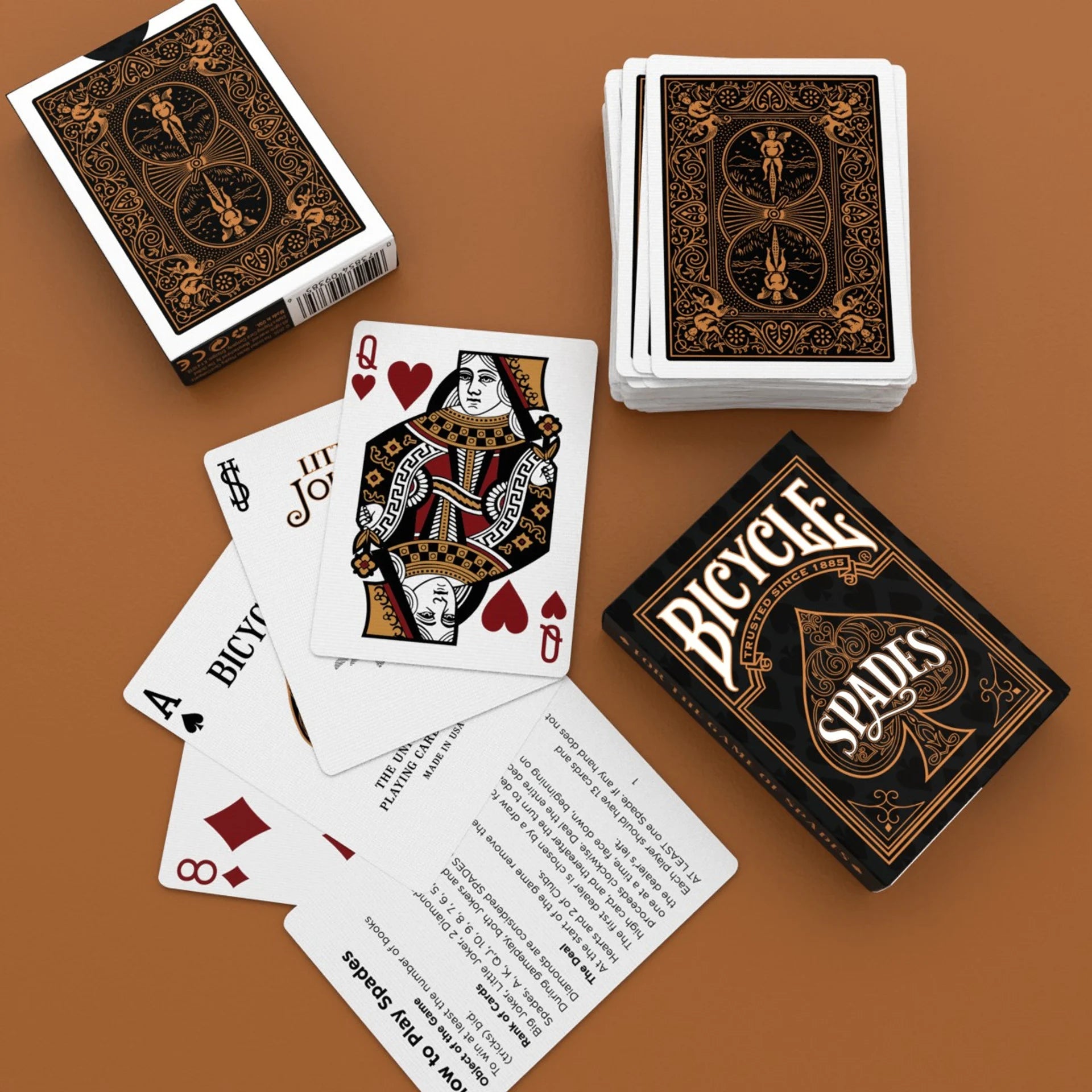 Bicycle Spades playing cards on a brown surface with some cards spread out.