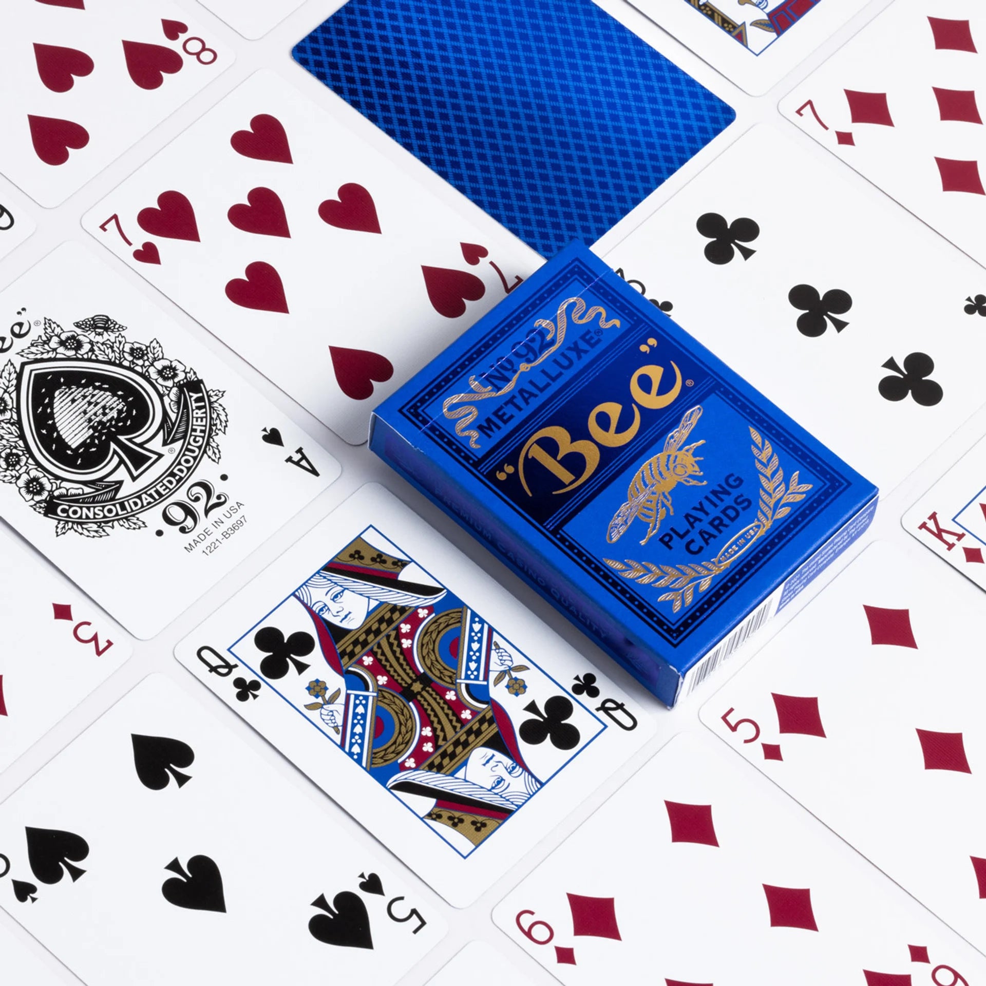 Blue Bee Metalluxe playing card box with cards featuring various suits on a white background