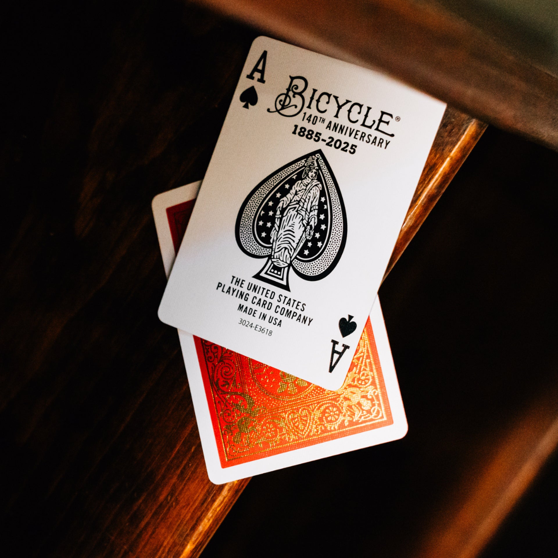 Bicycle playing cards with a 140th anniversary design on a wooden surface
