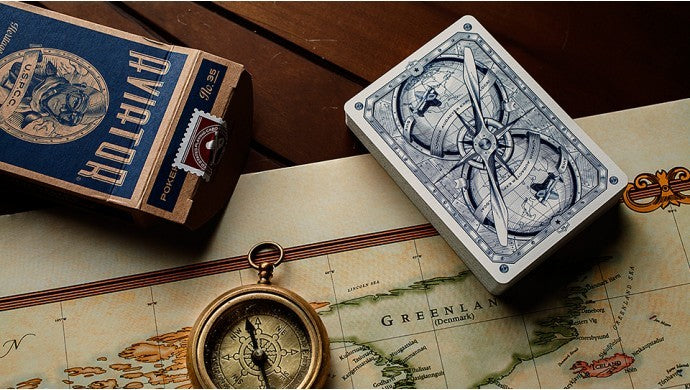 Playing cards with compass design on a map and vintage book