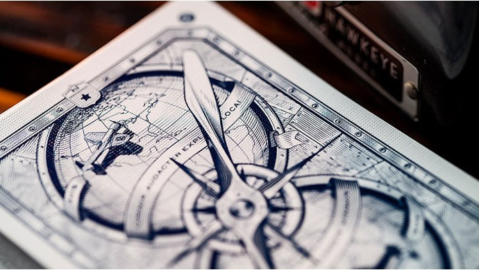 Close-up of a playing card with a detailed compass design on a wooden surface.