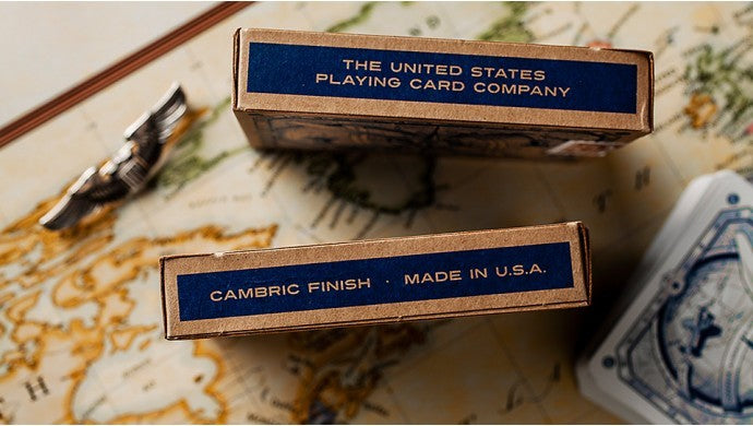 Two boxes of playing cards from The United States Playing Card Company on a map background.