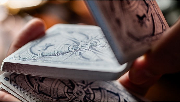 Close-up of hands holding a deck of playing cards with intricate designs.