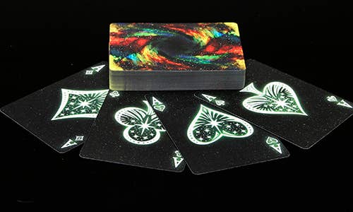 Playing cards with black backs and colorful design on top, on a black background