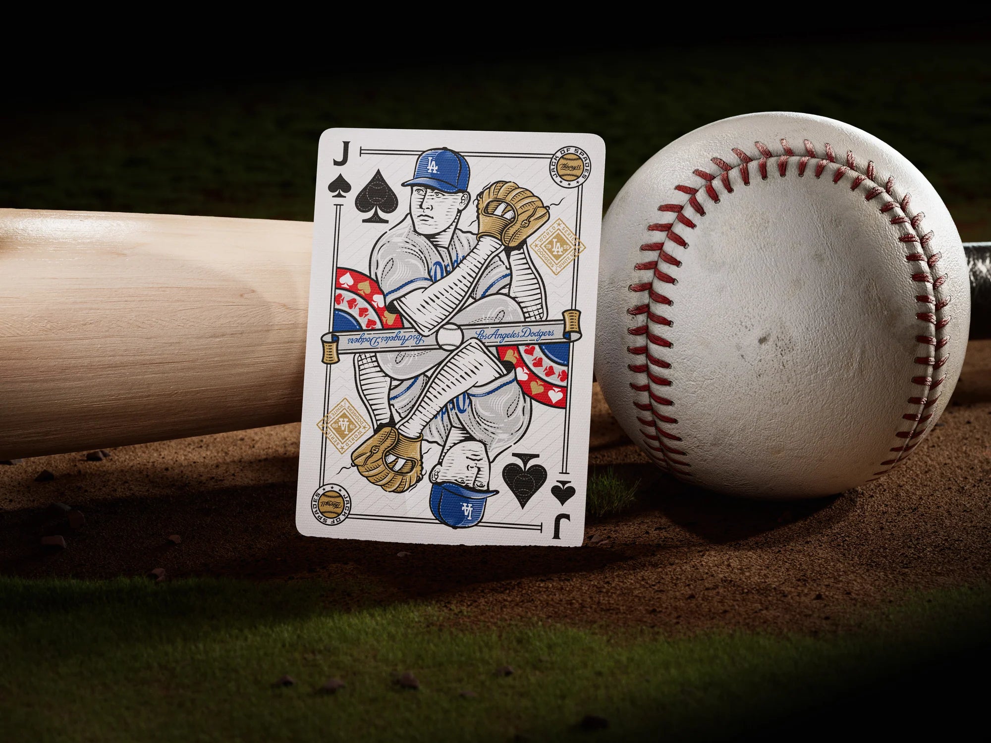 Wide shot of Dodgers Jack of spades standing upright on the grass with bat and baseball in the background.