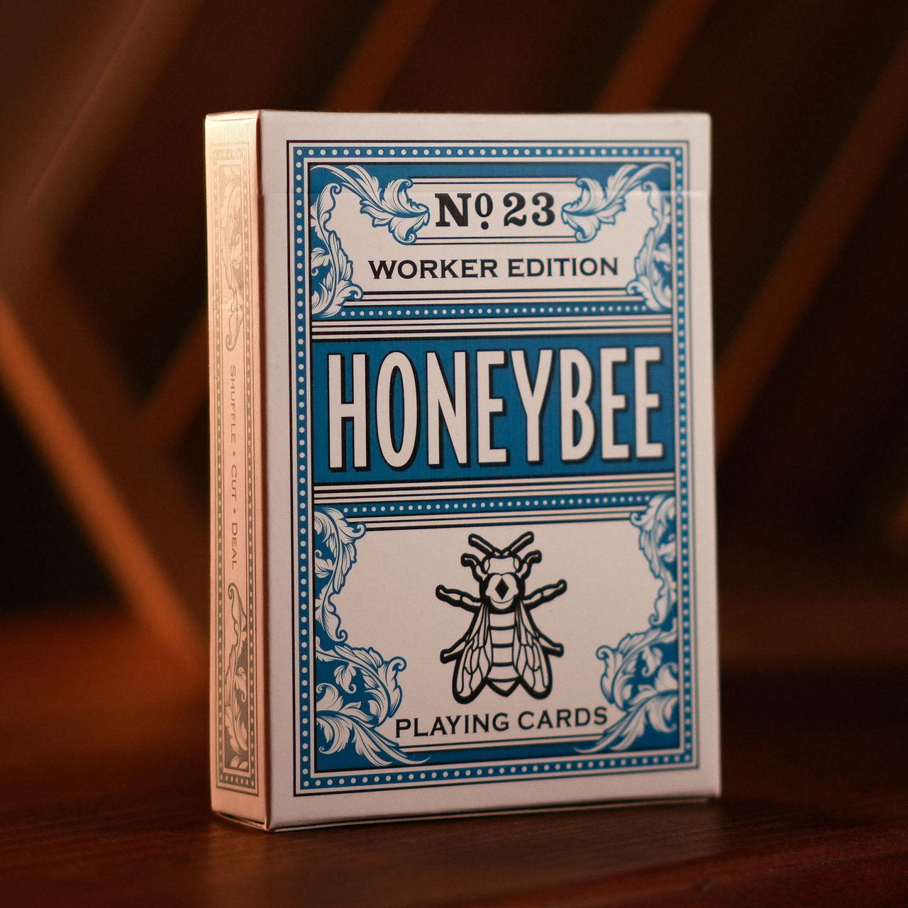 Honeybee playing cards packaging with blue and white design on a wooden surface