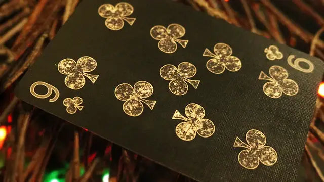 Black playing card with gold clover symbols on a textured background