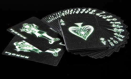 Black playing cards with green designs on a black background