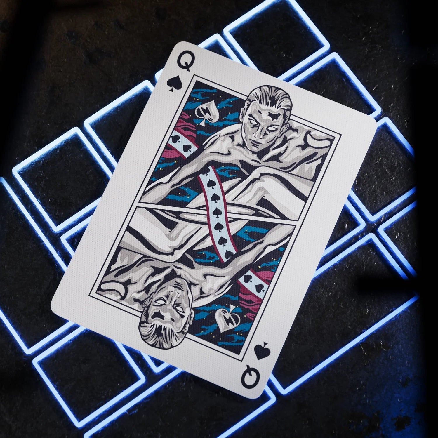 Playing card with a stylized design on a dark surface with neon blue lights.