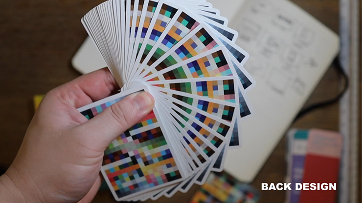 Hand holding a deck of cards with color swatch designs on the back