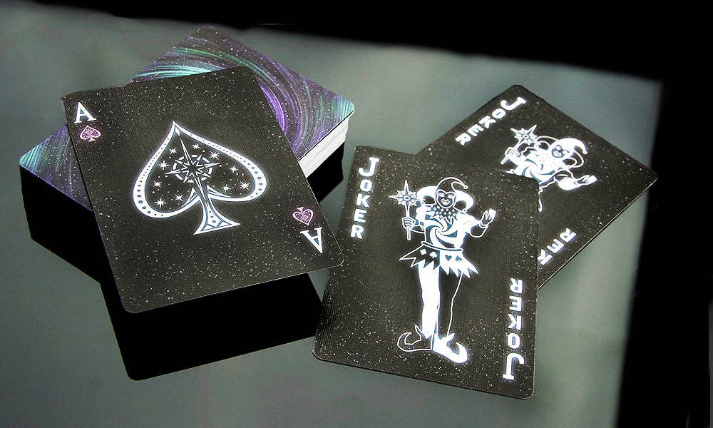 Black playing cards with white designs on a reflective surface