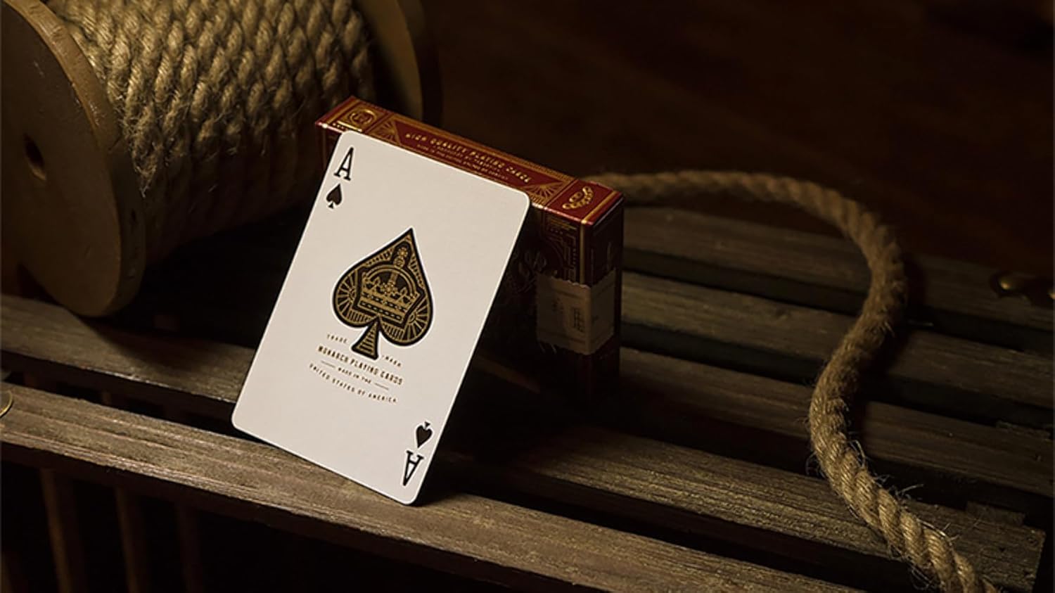 Playing card with ace of spades design on a wooden surface with rope and wooden spool.