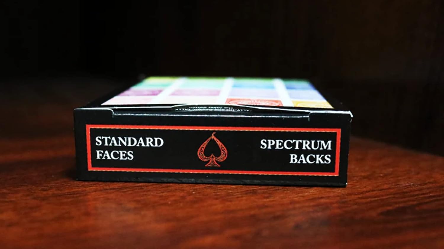 Card deck packaging with 'Standard Faces' and 'Spectrum Backs' text on a wooden surface.