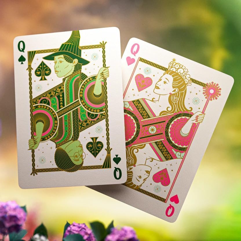 Two playing cards, Queen of Spades and Queen of Hearts, with a blurred floral background.