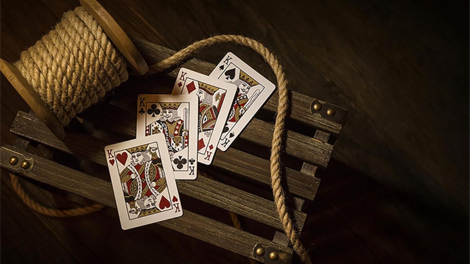 Playing cards on a wooden surface with rope and spool of thread.