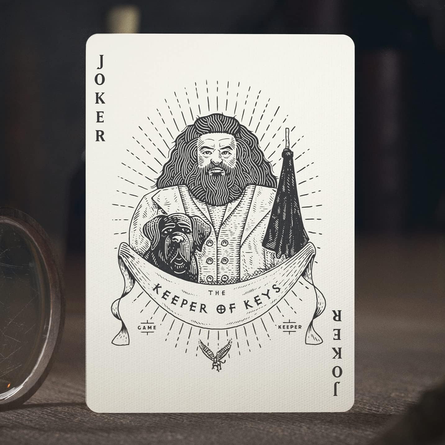 Playing card with a design of a bearded man and dog, labeled 'Joker Keeper of Keys', on a dark background.