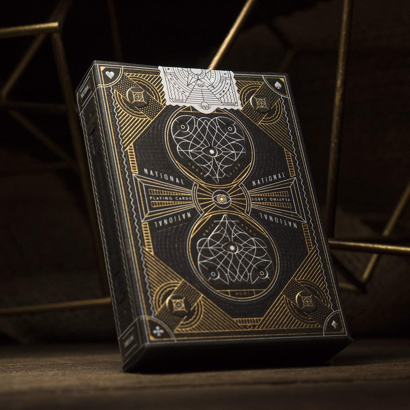 Black and gold playing card box with intricate designs on a dark background