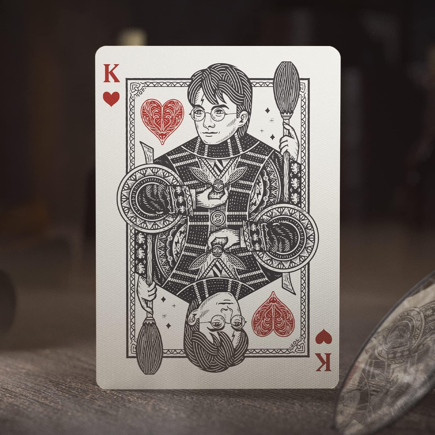 Playing card featuring a character with a broom and heart symbol on a dark background