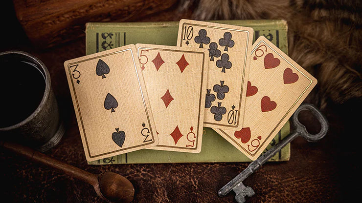 Playing cards on a wooden surface with a mug, spoon, and key.