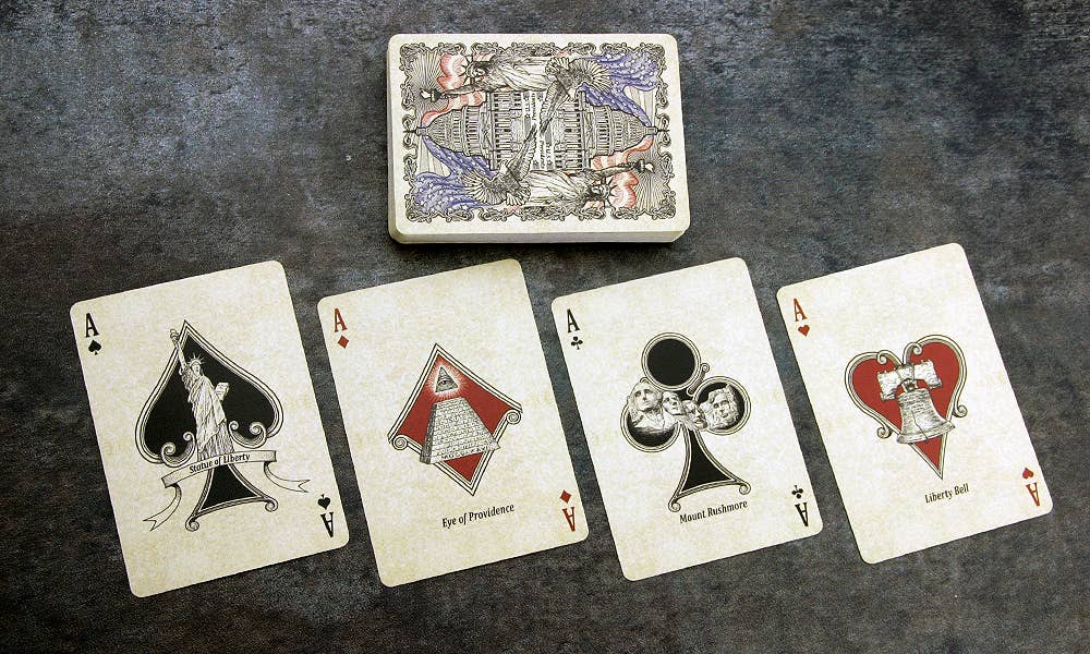 Four playing cards with unique designs on a textured surface