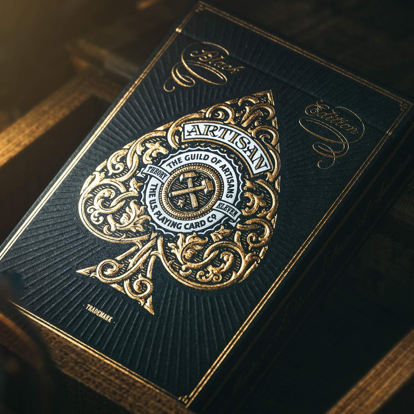 Playing card box with 'Artisan' branding on a wooden surface