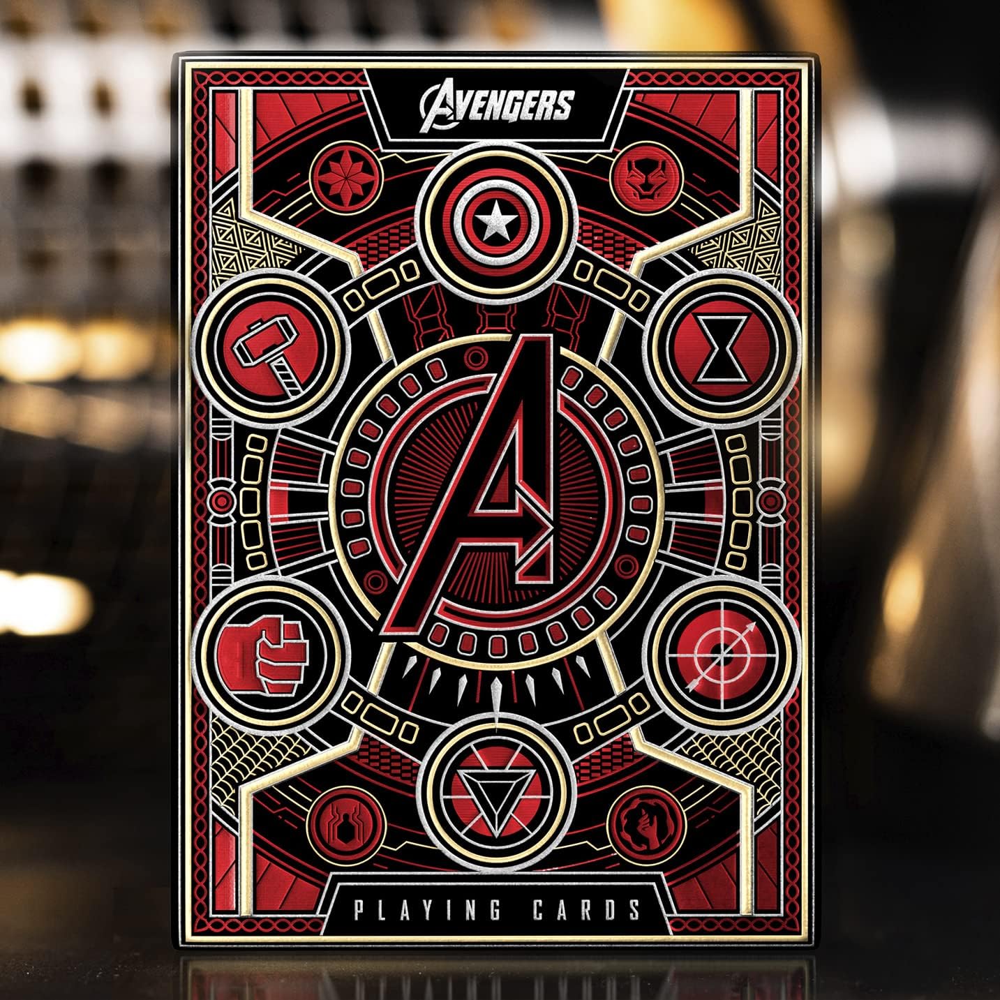 Avengers-themed playing cards with red, black, and gold design on a blurred background