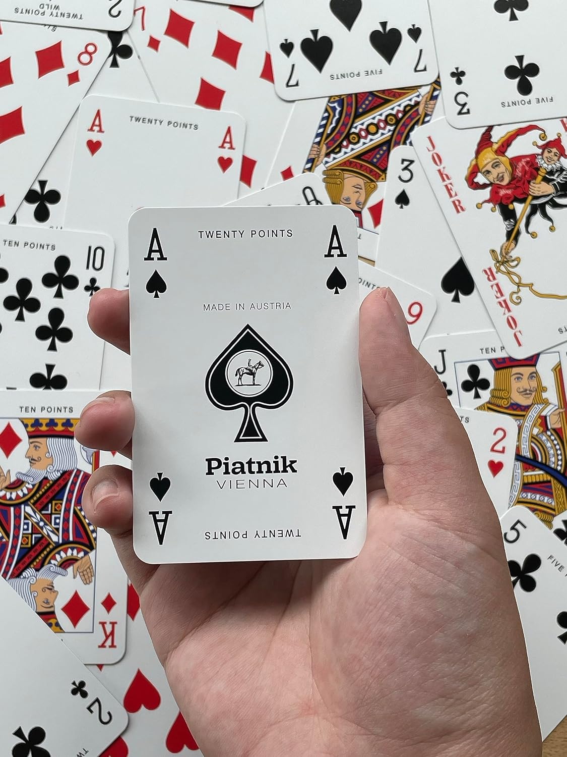 Hand holding a Piatnik Vienna playing card with other cards in the background