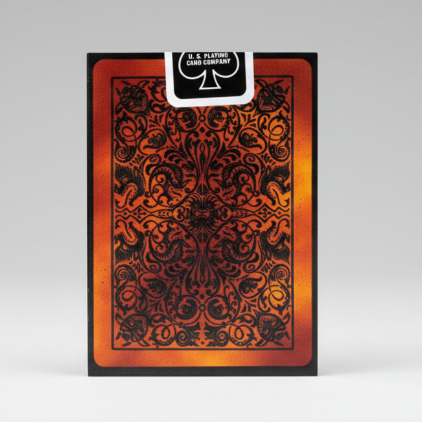 Playing card with intricate black design on a red-brown background, featuring U.S. Playing Card Company branding.