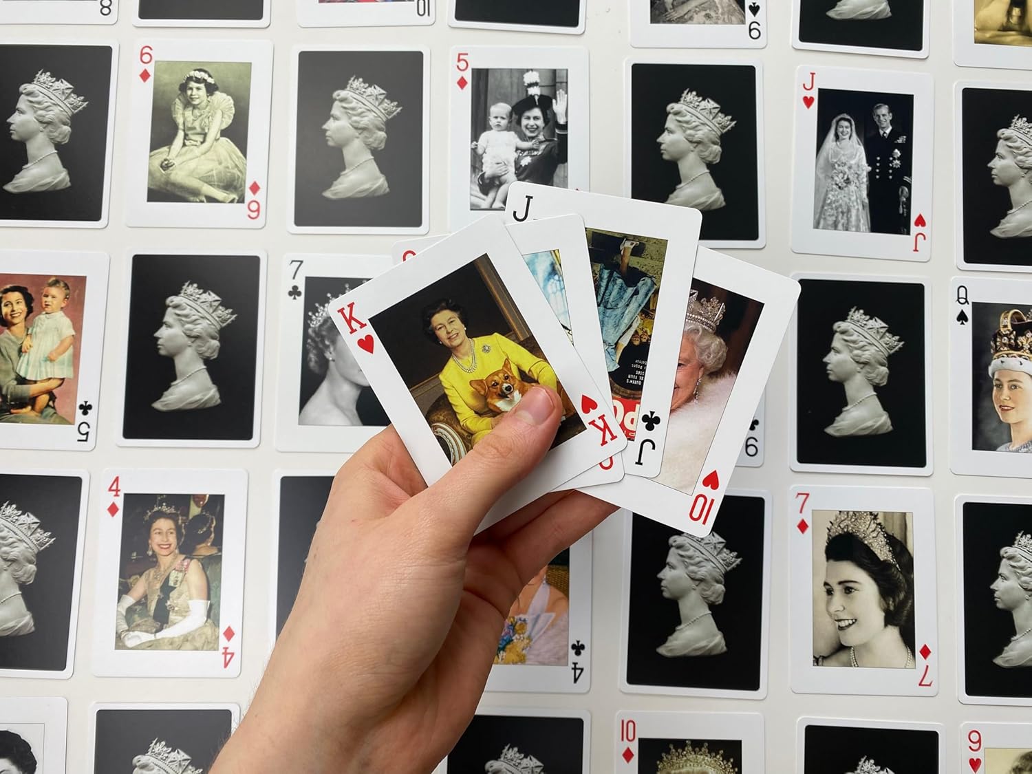 Hand holding playing cards over a grid of vintage portraits