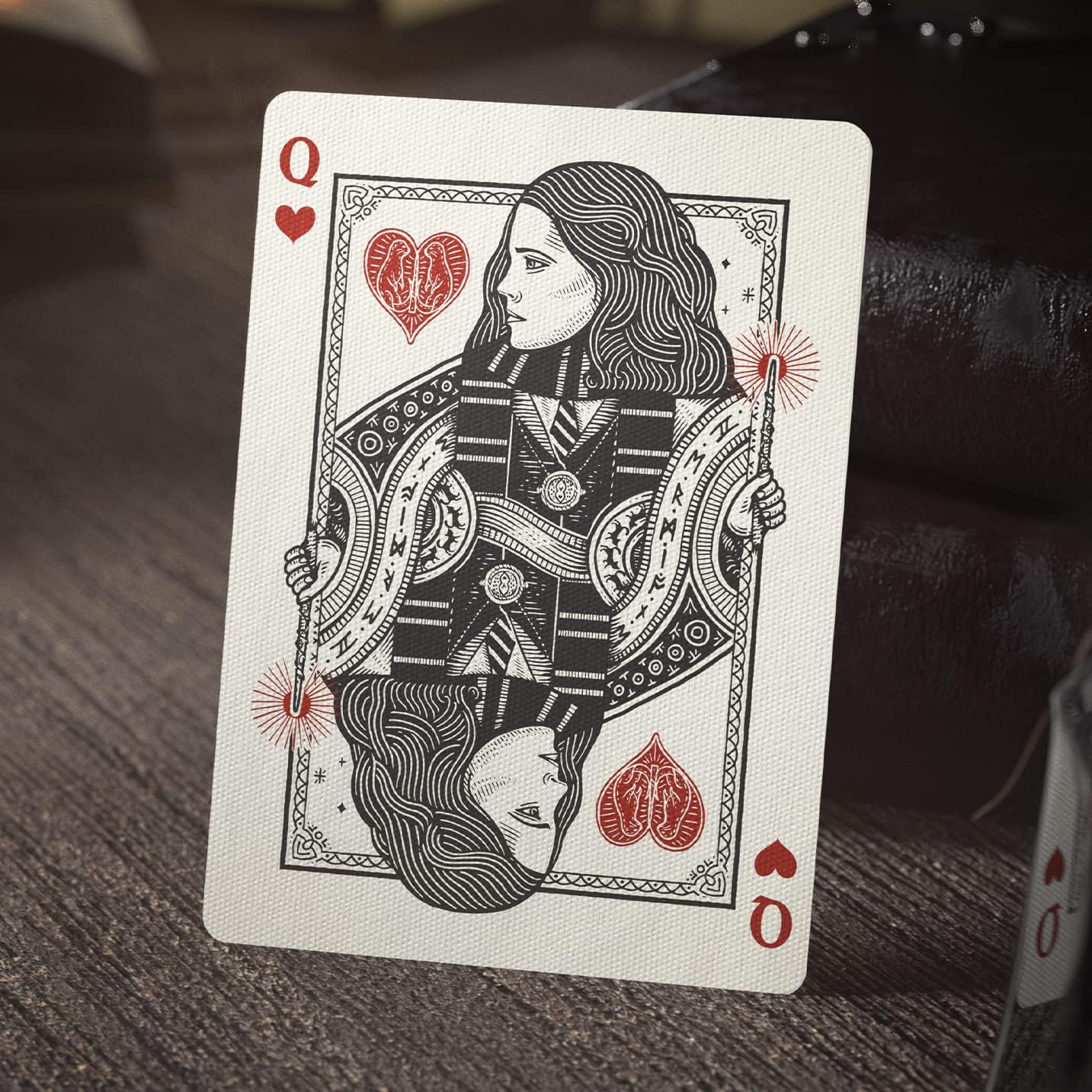 Queen of Hearts playing card with intricate design on a textured surface