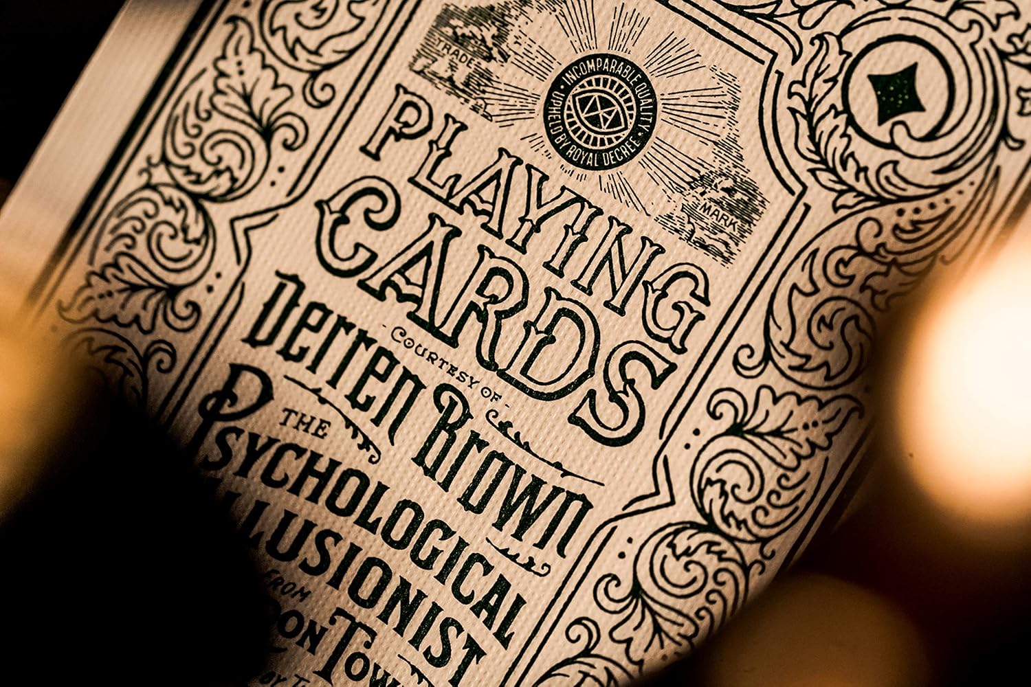 Close-up of typography and ornament on Derren Brown ad card highlighting ‘Playing Cards’ lettering.