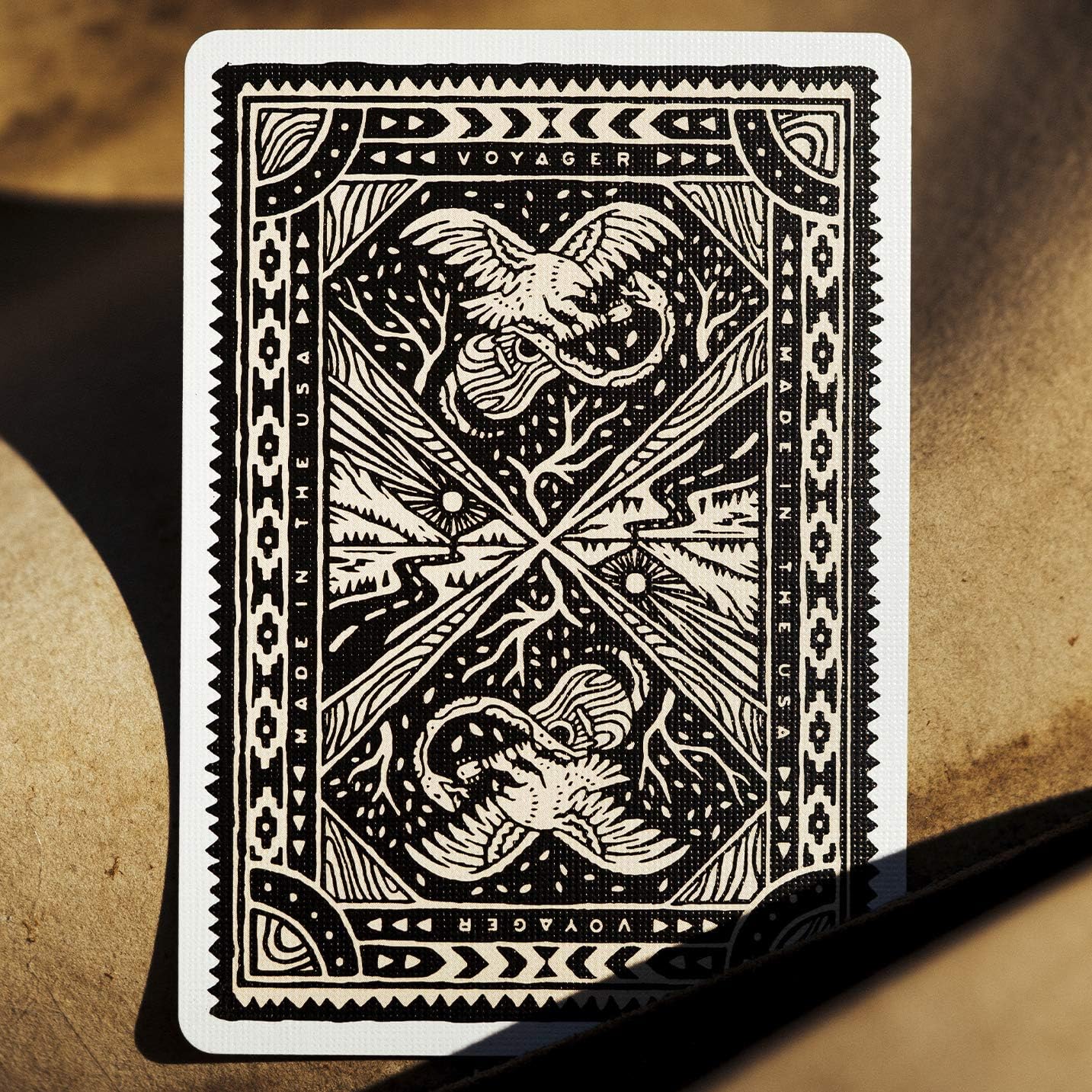 Playing card with intricate black and white design on a textured surface