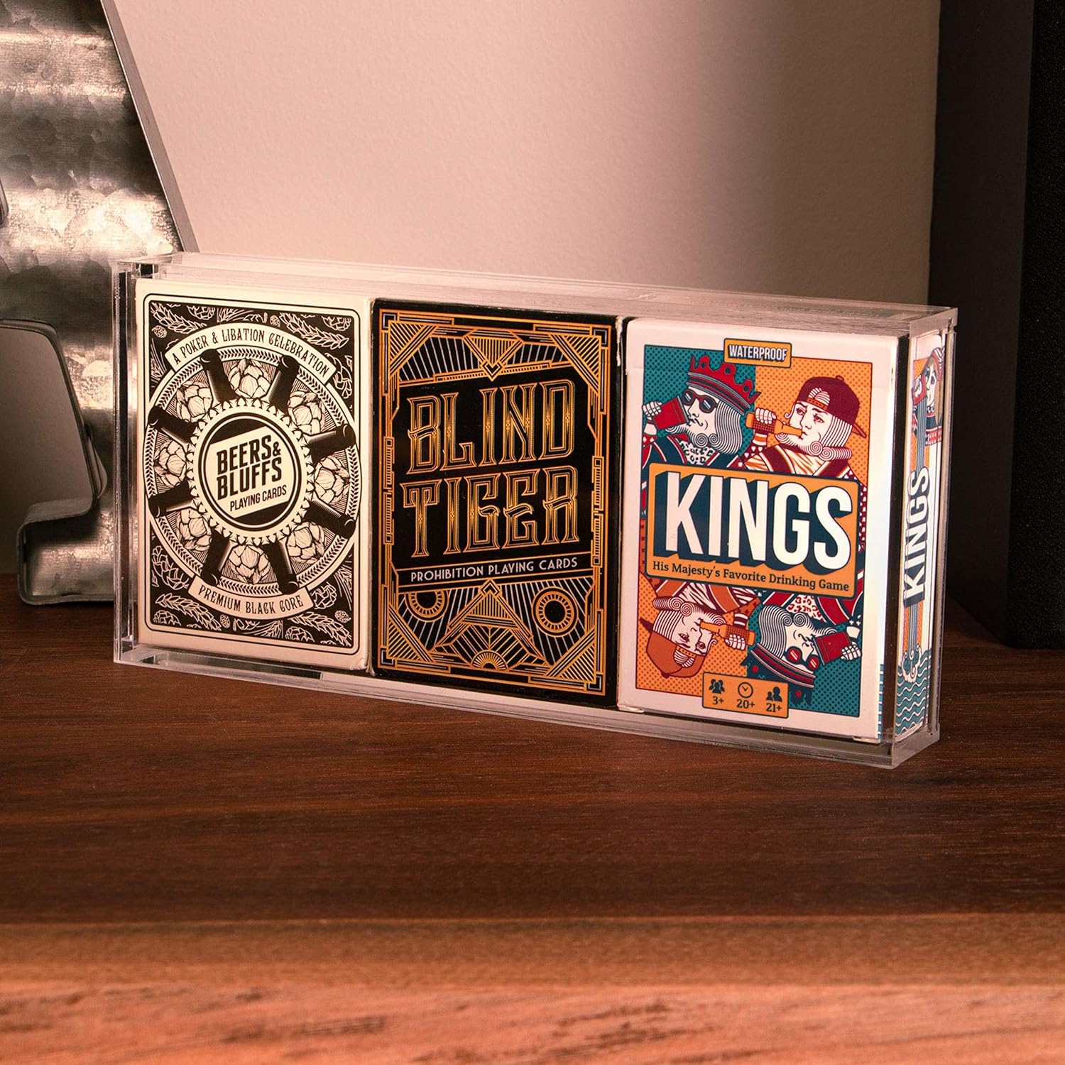 Three playing card decks in decorative boxes on a wooden surface