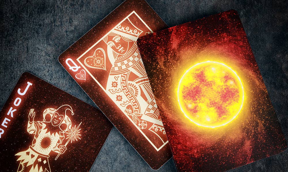 Three playing cards with different designs on a dark textured surface