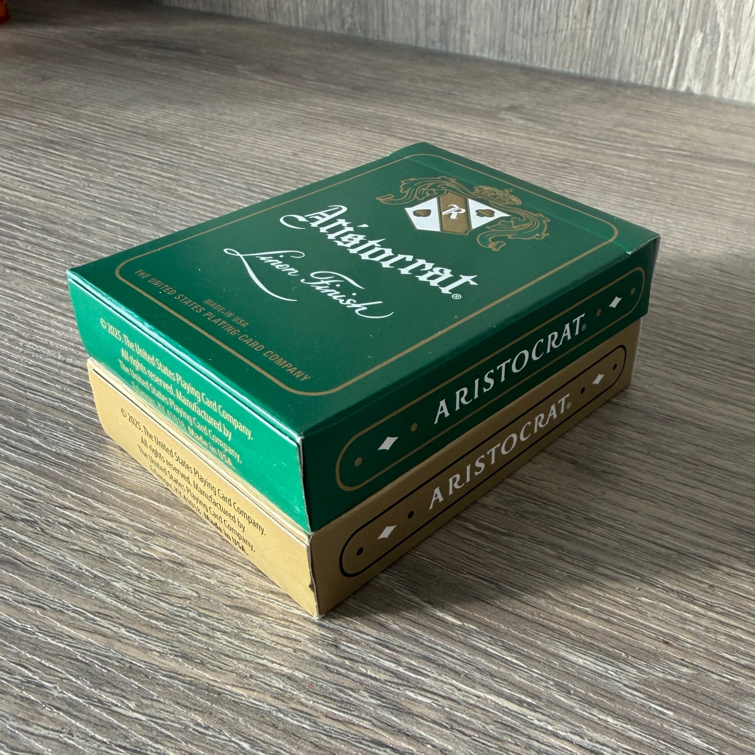 Aristocrat 727 Currency Green & Gold playing card decks stacked on a wood table