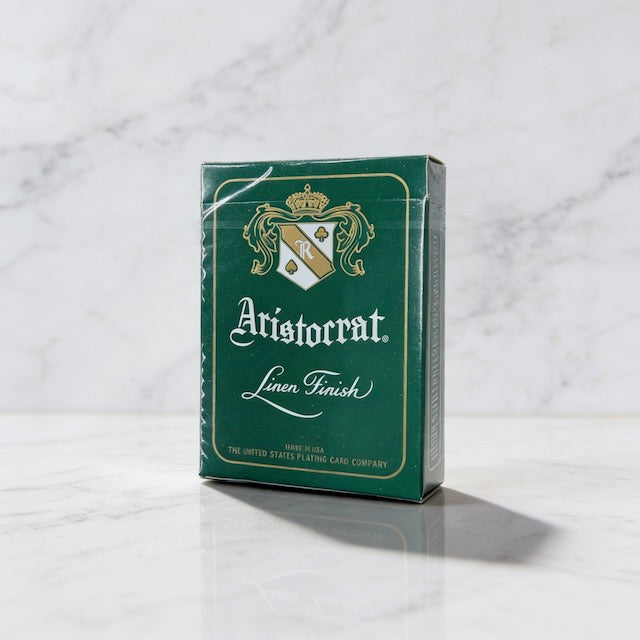 Currency green box of Aristocrat 727 playing cards on a marble surface