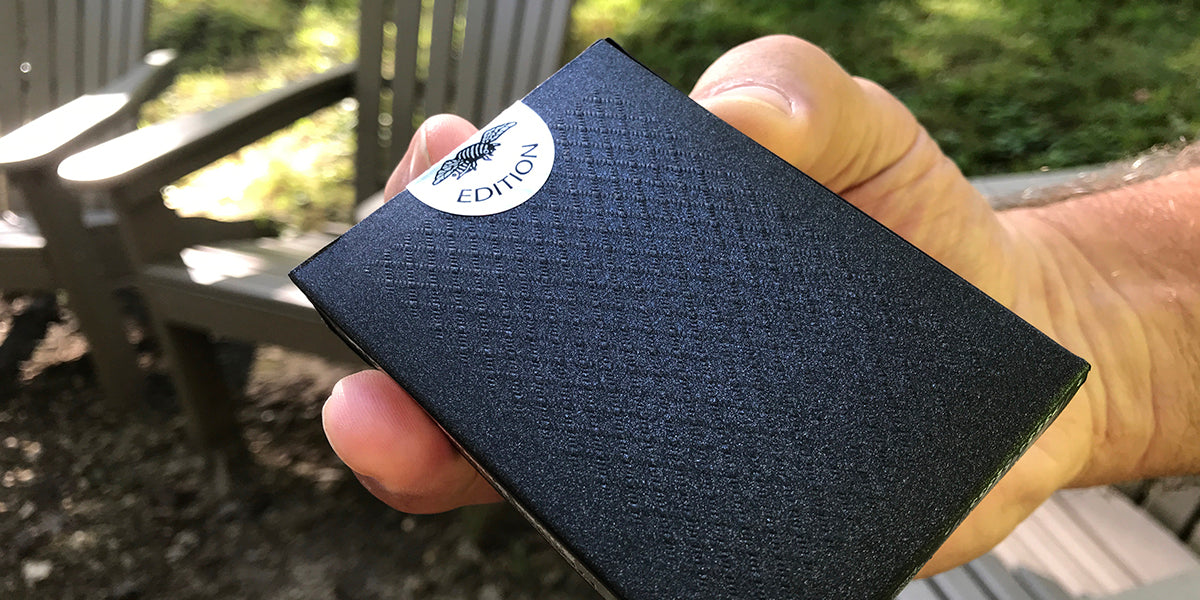 Person holding a black textured wallet with a visible brand logo.