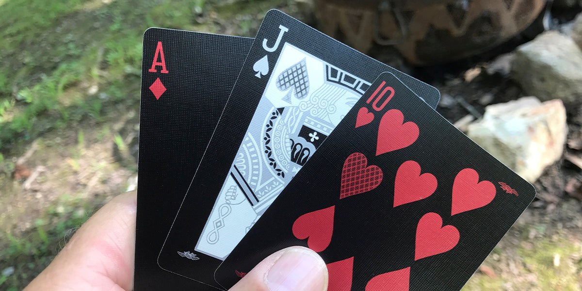 Hand holding a set of playing cards with a blurred natural background