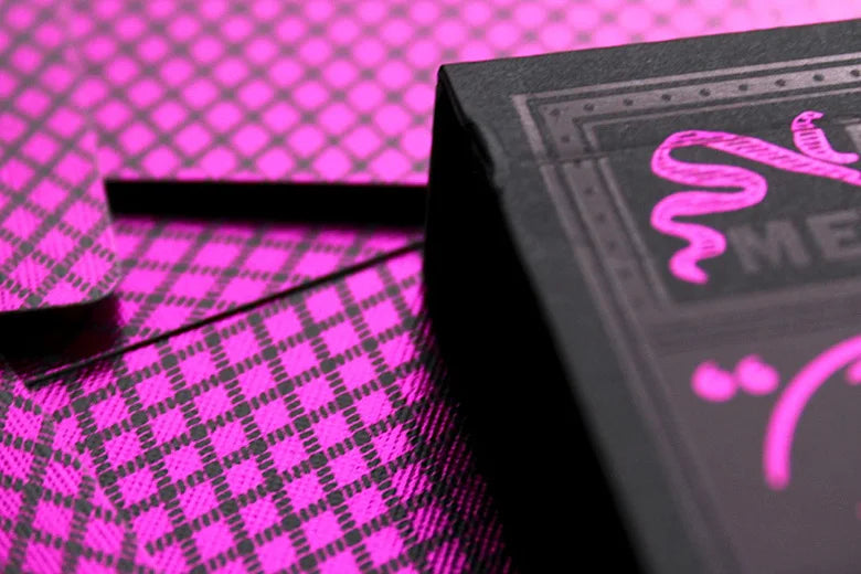 Close-up of a black Bee Magenta & Black Metalluxe box with magenta text and design on a magenta checkered background