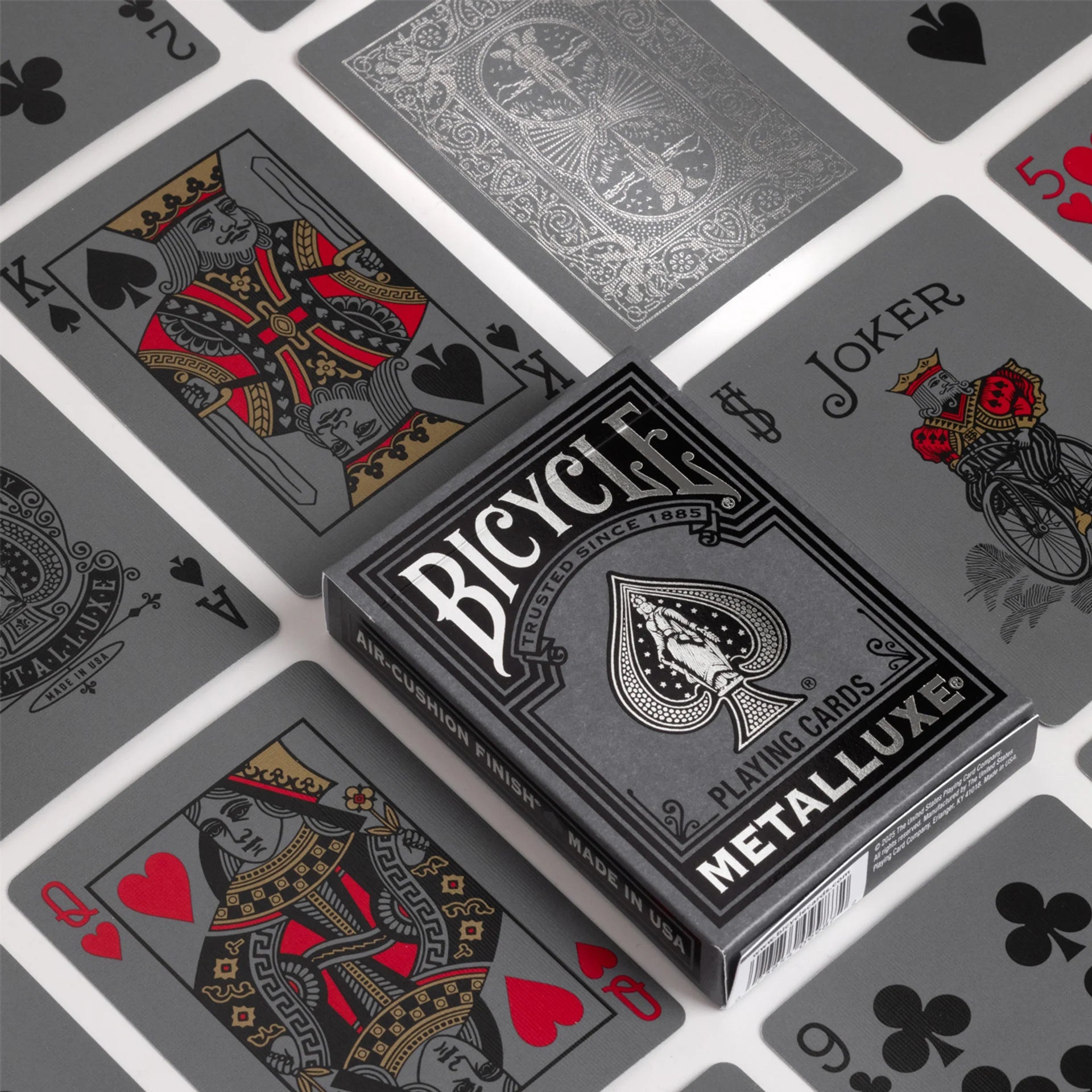 Bicycle Black & Silver Metalluxe playing cards with card designs in the background
