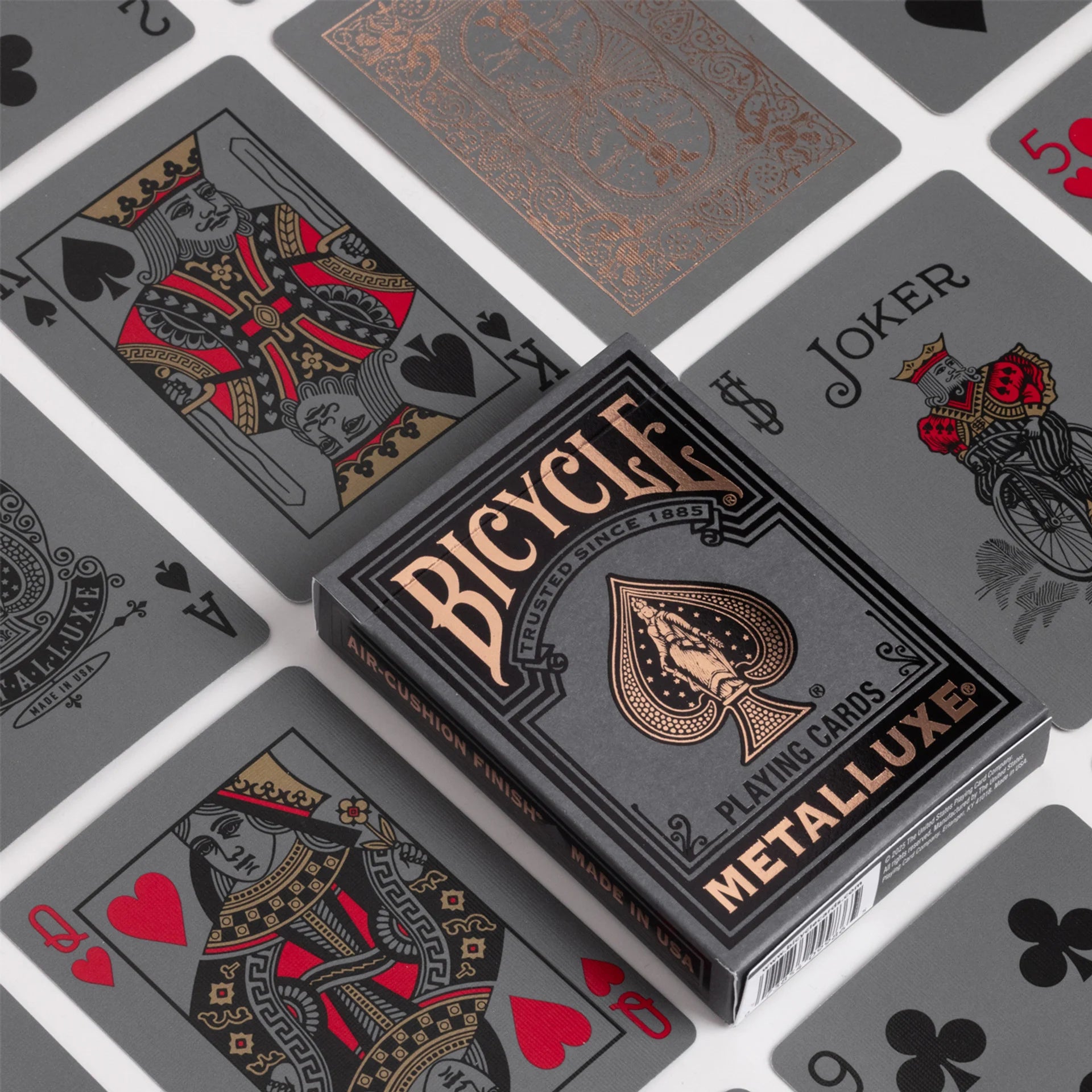 Bicycle Black & Rose Gold Metalluxe playing cards with card designs in the background