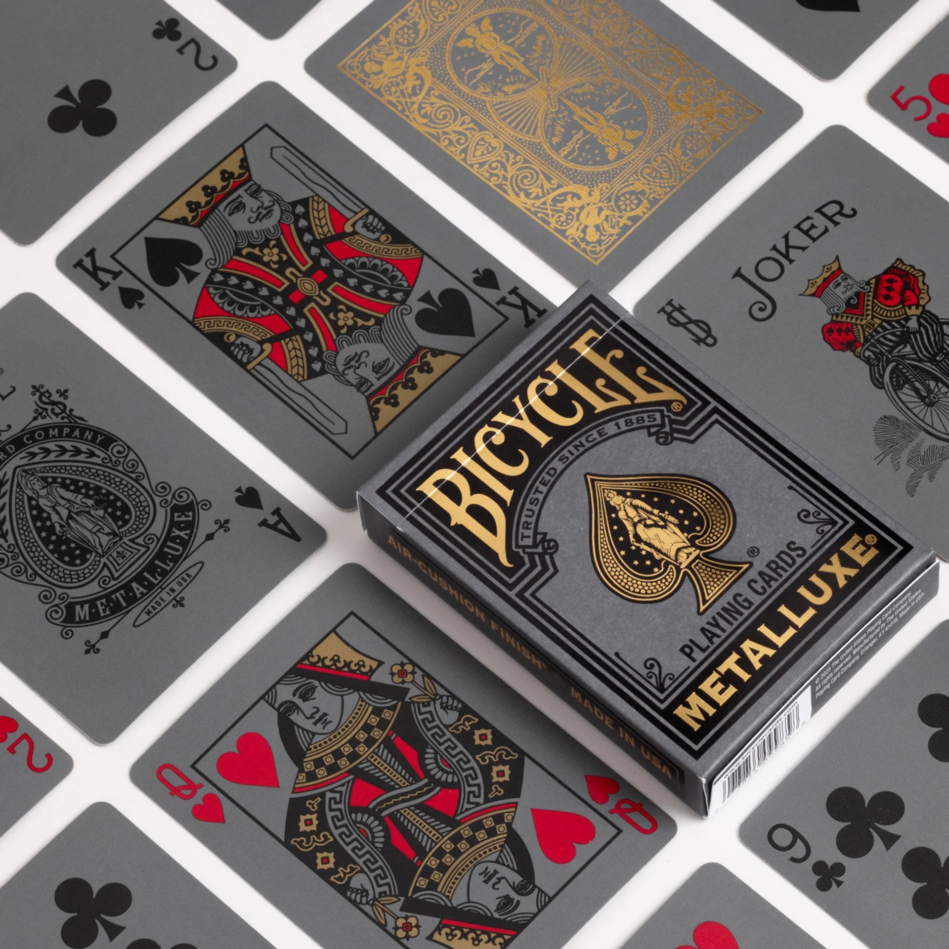 Bicycle Black & Gold Metalluxe playing cards with card designs in the background