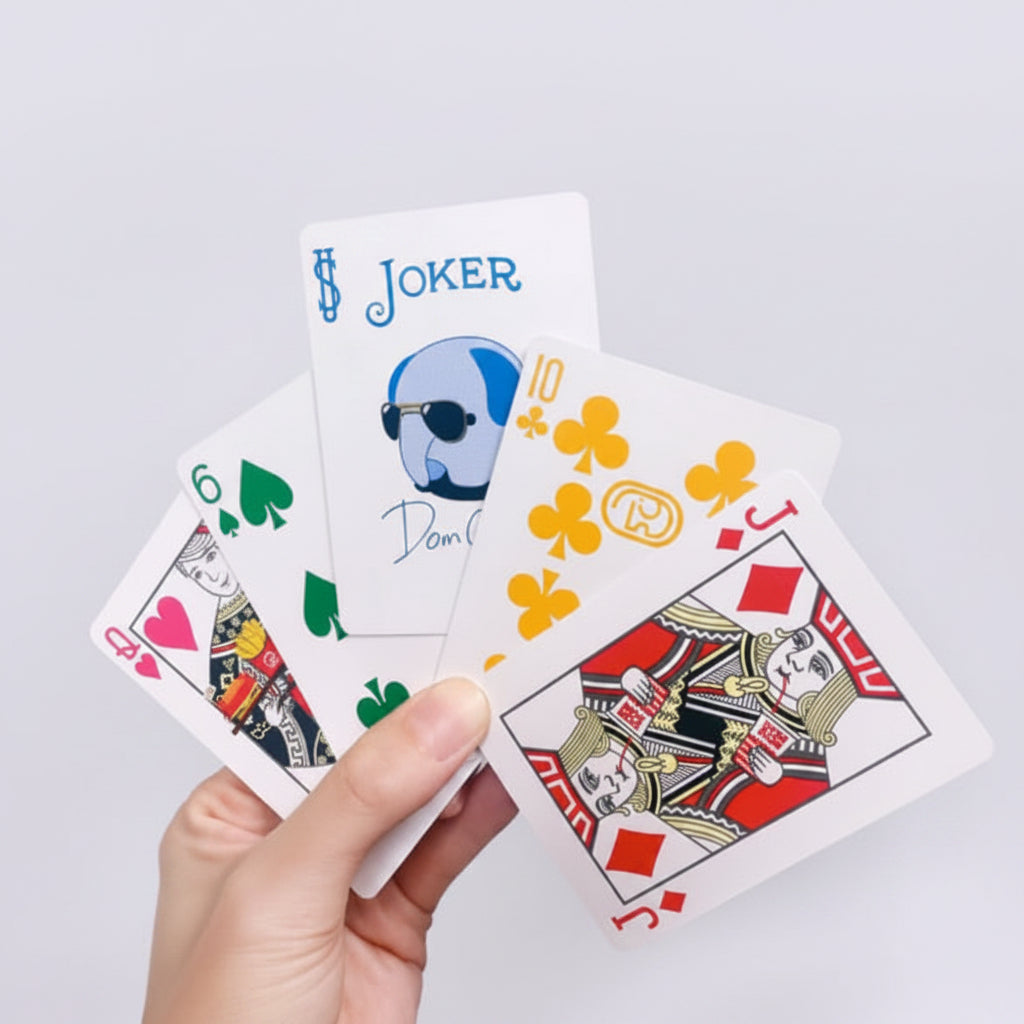 Bicycle Dom Dom Burger Playing Cards fanned in hands showing joker, custom court card, and colorful four-suit design