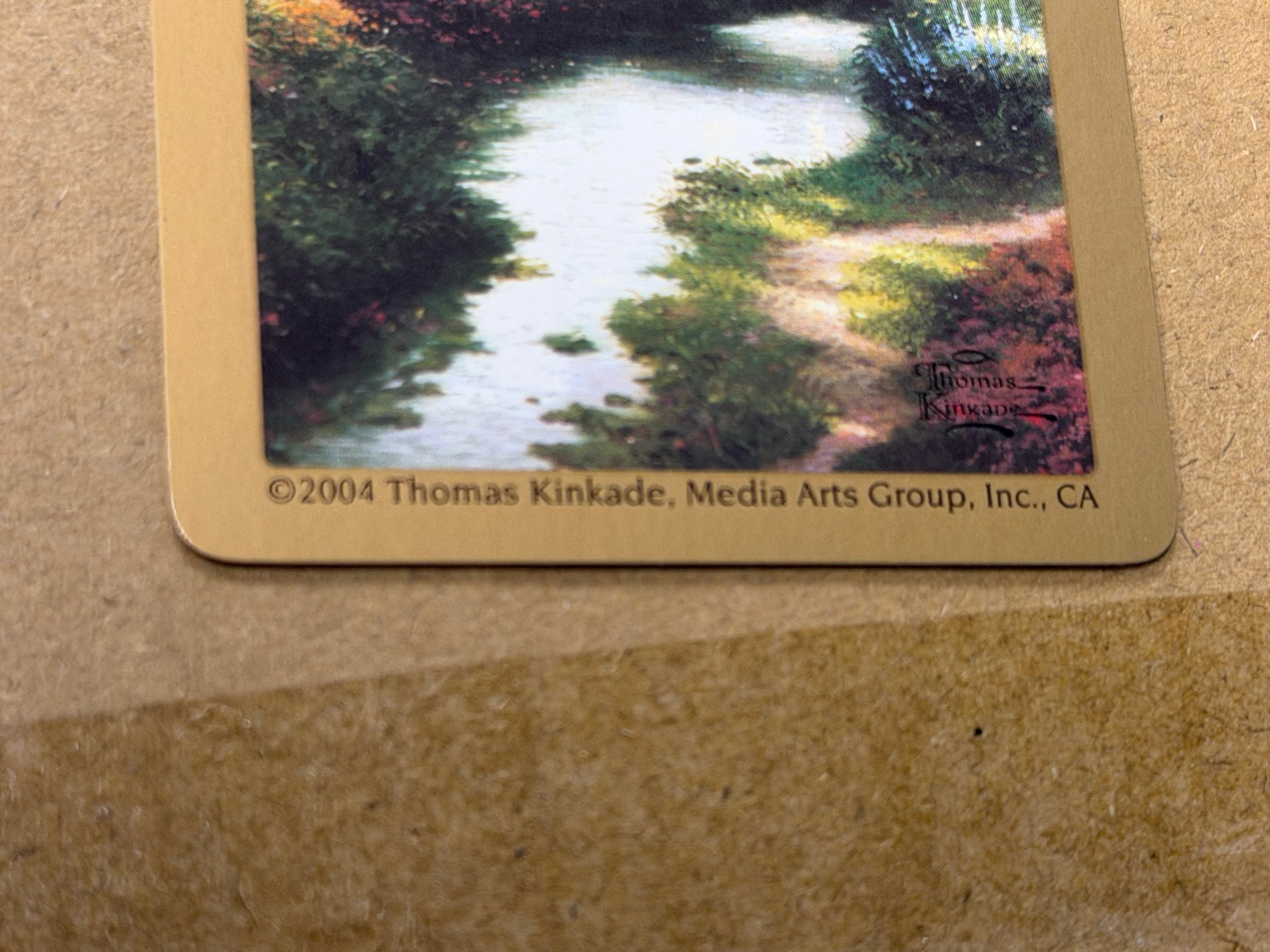 Close-up of 2004 Thomas Kinkade Media Arts Group copyright and artist signature on Congress Gardens card back