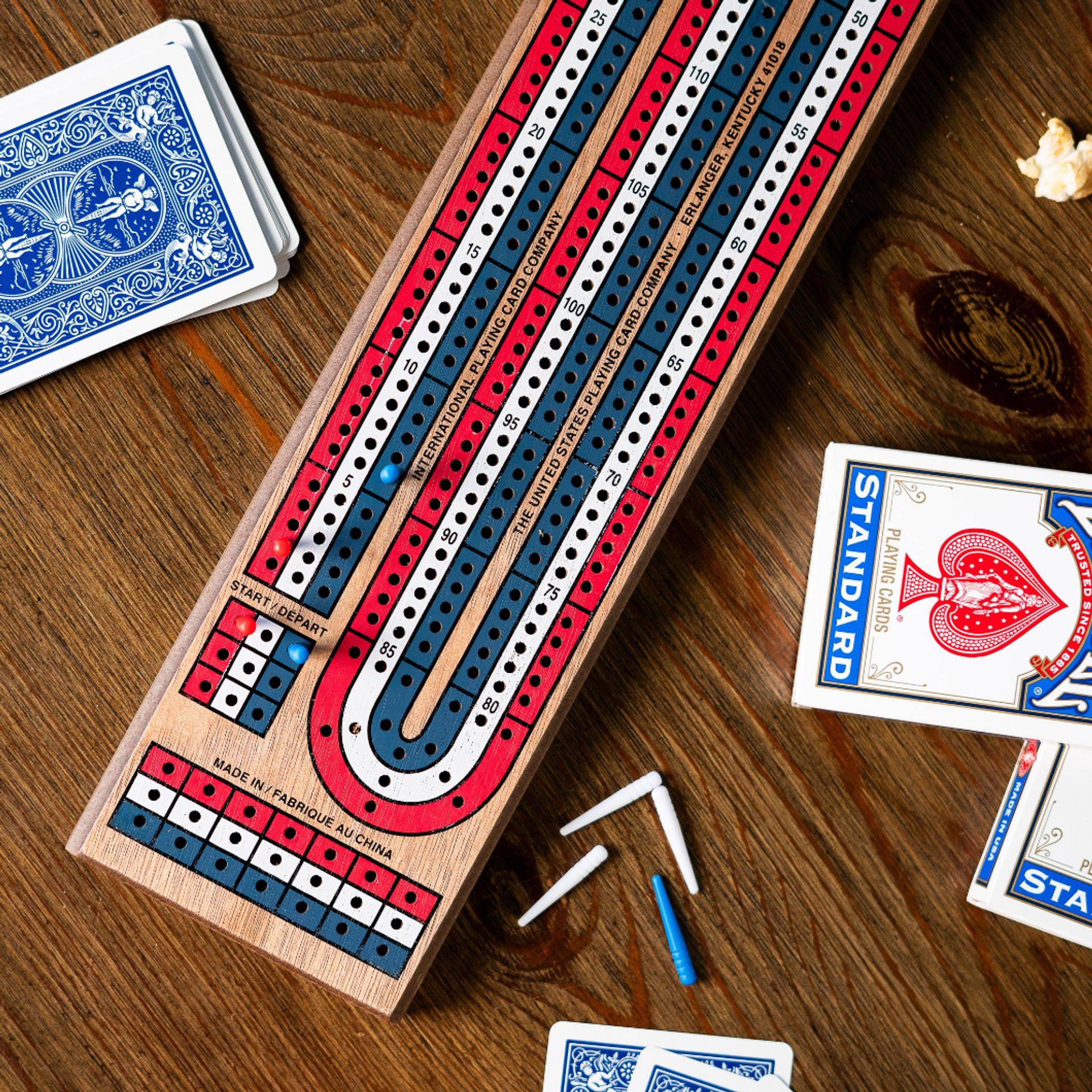 Cribbage board with pegs and cards on a wooden surface