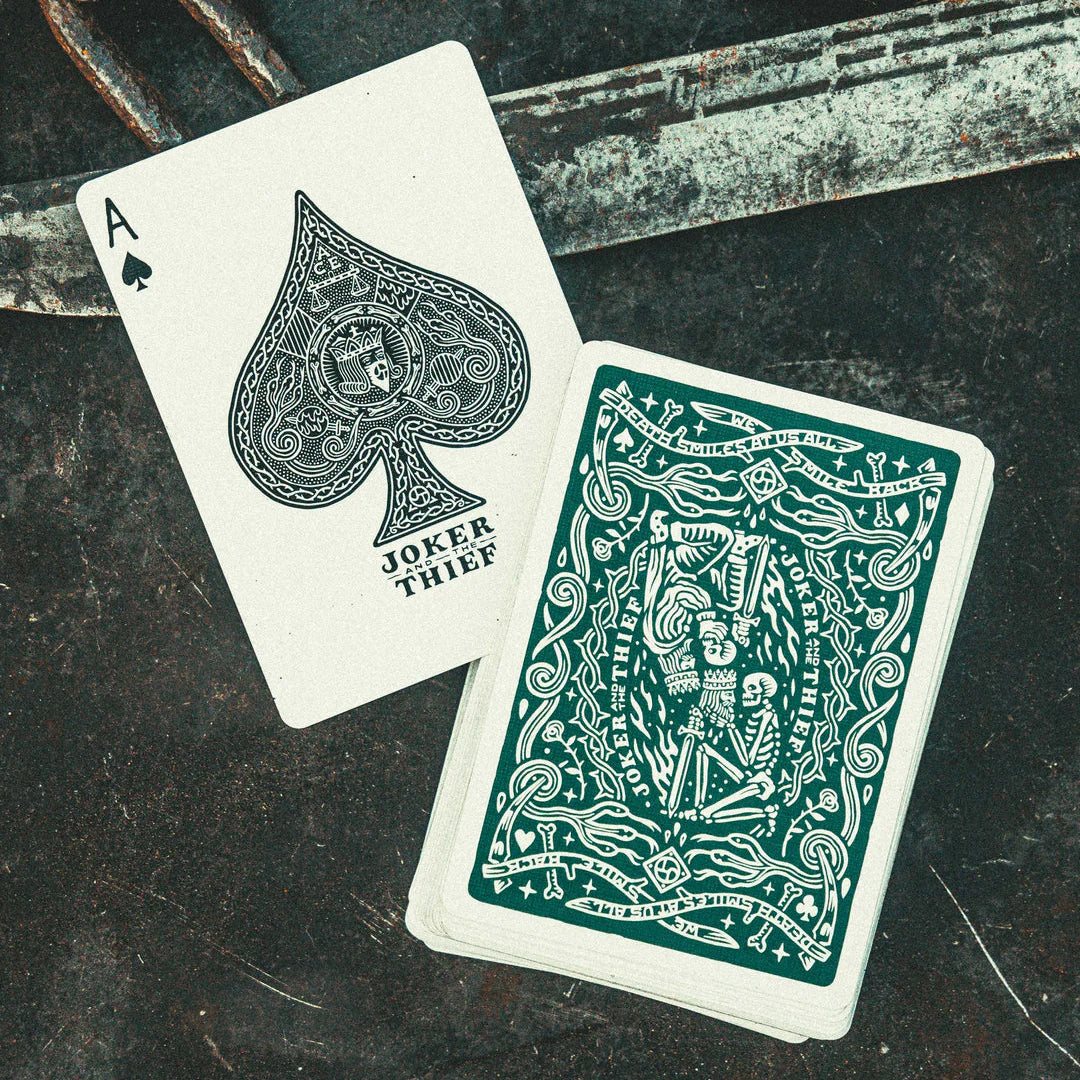 Two playing cards from the Joker and the Thief deck on a dark surface.
