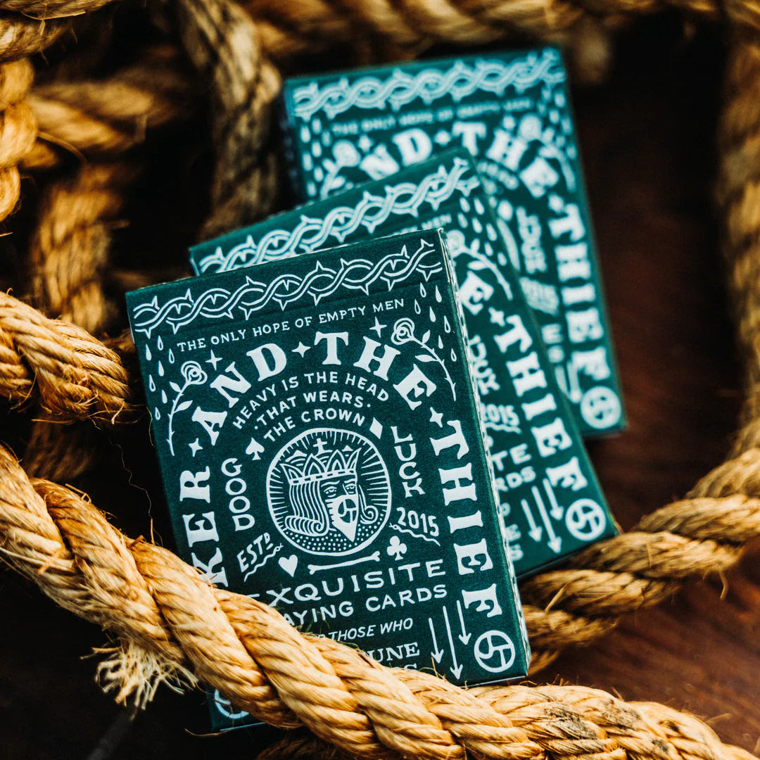 Two decks of 'Joker and the Thief' playing cards on a rustic wooden surface with rope.