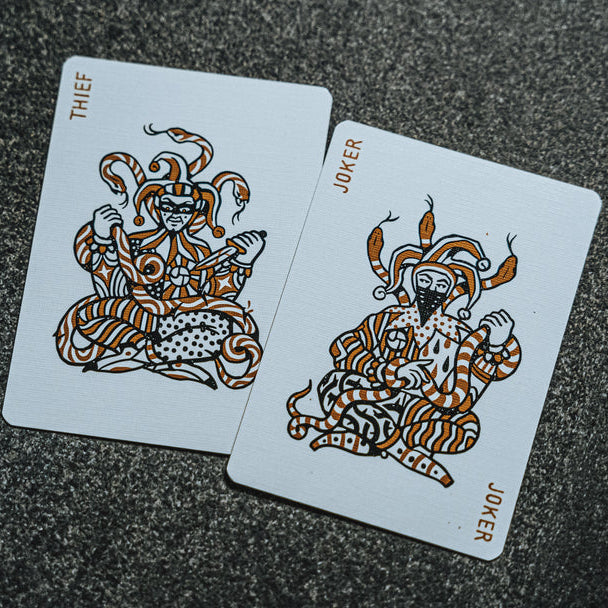 Two playing cards, 'Thief' and 'Joker', on a textured surface.