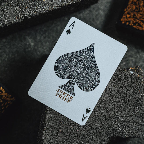 Ace of Spades playing card from Joker & Thief deck on a dark textured surface.
