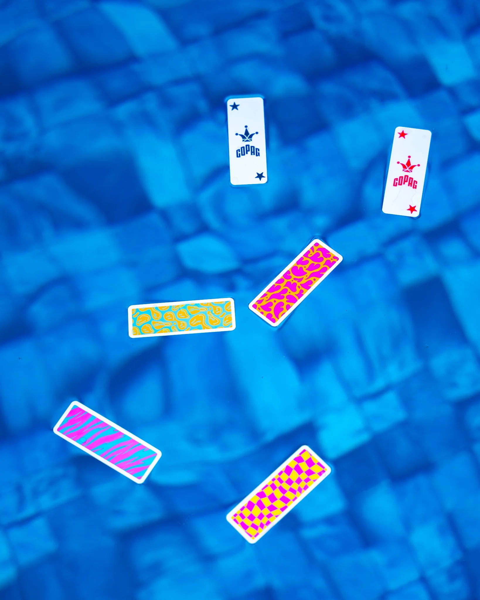 Colorful Copag Go Deck playing card designs on a blue mosaic tile background